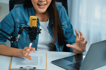 Host channel Asian influencer talking in broadcast streaming online wearing headset on social media live with script note, greeting listeners in life coaching or marketing at modern studio. Stratagem.