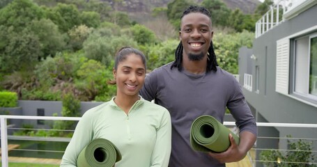 Stepping onto balcony, diverse couple walking together and positioning yoga mats for practice - Powered by Adobe