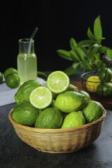 Fresh Lime Fruits in Basket with Juice and Tropical Plants on Dark Background
