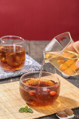 Herbal Tea Pouring from Glass Teapot with Goji Berries and Mint Leaves