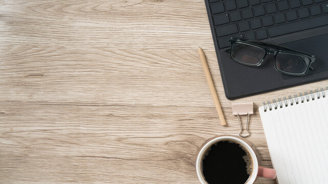 Elevated view of a bright desk with coffee, notepad, glasses, and laptop for a focused workday and creative inspiration and productivity