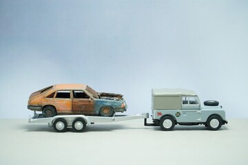 Mini toy of action figure at outdoor with blurred background. Miniature photography concept design. Minifigure of worker character with damage car at towing truck.