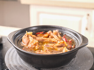 Spicy Duck Stew with Flavorful Sauce Cooking in Black Pot on Kitchen Stovetop
