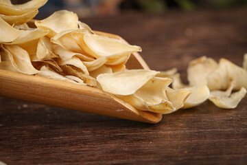 Chinese Baihegan Dried Herb Medicine Slices in Wooden Spoon Traditional Health Tonic Display Closeup