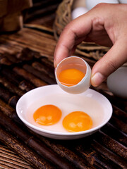 Fresh Raw Eggs Being Cracked into Bowl on Rustic Wood Background