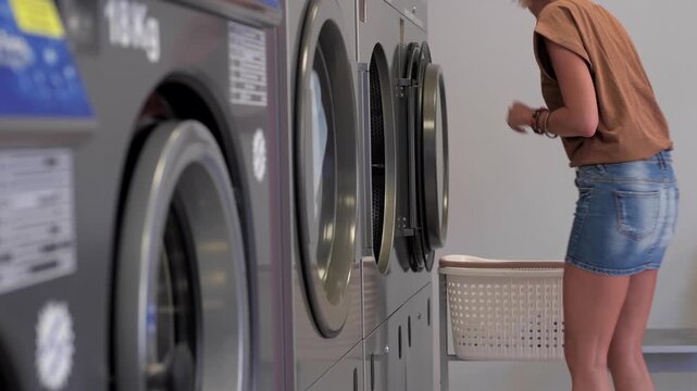 Woman putting white clothes into dryer at laundromat