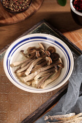 Traditional Asian mushroom soup with sliced shiitake mushrooms in ceramic bowl on wooden tray
