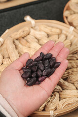 Yunnan Black Selenium-Enriched Peanuts in Hand with Dried Peanuts in Wicker Basket - Healthy Grains and Cereals