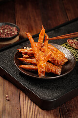 Marinated Chicken Feet with Sauce - Traditional Asian Cuisine Snack on Dark Plate with Chopsticks