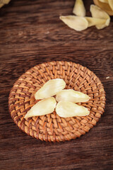 Fresh dried ginger slices in wicker basket - Chinese herbal medicine closeup on wood background