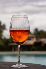Glass of rosé wine by the swimming pool in summer sunlight.