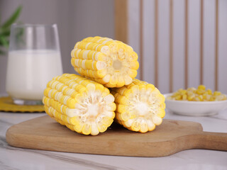 Fresh Sweet Corn Cob Slices on Wooden Board in Modern Kitchen