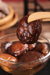 Fresh Shiitake Mushrooms in Glass Bowl with Wooden Spoon for Fondue Cooking Preparation