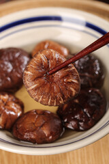 Fresh shiitake mushrooms in hot broth pot with chopsticks on white background - Asian cooking ingredients