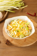 Scrambled eggs with fresh chives and garlic in bowl on wooden board - healthy breakfast main dish