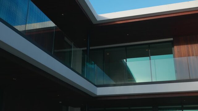 Modern building with flat roof and open courtyard. Design uses glass walls, wooden panels and clean lines. Space looks bright and peaceful with lots of natural light