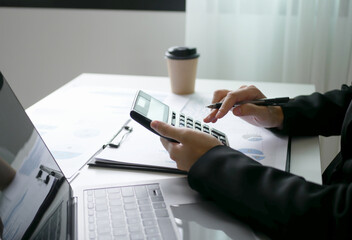 Young Asian business woman sitting at the table holding a pen, recording investments and planning the process of growing a successful business