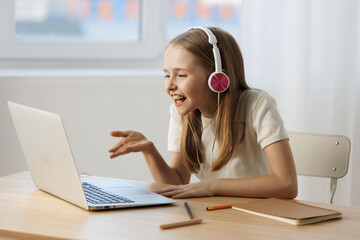 Happy girl with headphones engaging in an online class, showcasing joy and concentration, with a light background and a warm color palette