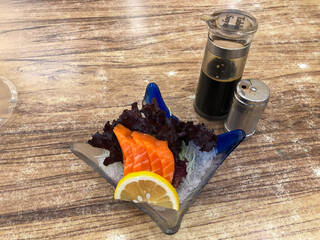 Fresh sashimi served with Japanese soy sauce and garnished with lemon slices and lettuce leaves, sashimi dish at a Japanese restaurant