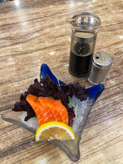 Fresh sashimi served with Japanese soy sauce and garnished with lemon slices and lettuce leaves, sashimi dish at a Japanese restaurant