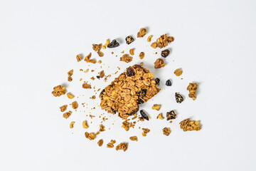 Granola bar with almonds, oats, and dried cranberries, isolated on a white background. Top view, high angle, above, Close up. clipping path. piece. Flat lay. broken. scattered. crumbs. cracked.