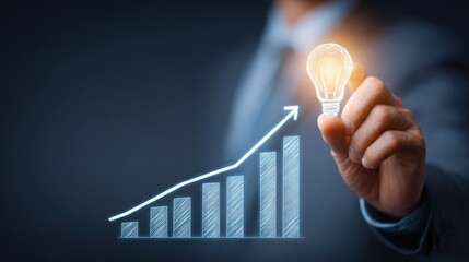 A businessman holding a light bulb with a growing bar graph in the background.