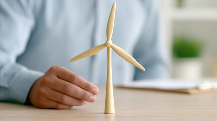 A person examines a miniature wind turbine model, symbolizing renewable energy and sustainable technology.