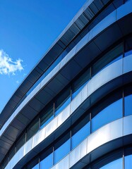 Abstract view of a modern building with curved architecture reflecting clear blue sky with minimal clouds on a sunny day