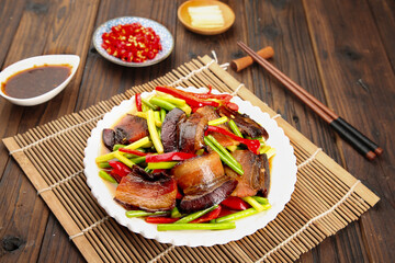 Chinese Stir-Fried Bacon with Garlic Scapes and Vegetables on Wooden Table