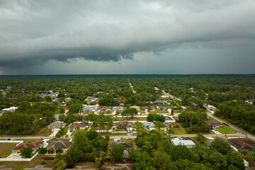Dark stormy clouds forming on gloomy sky before heavy rainfall over suburban town area