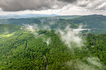 Road trip driving in Tennessee Appalachian mountains. Winding parkway in mountain forest with green canopies in summer rain season