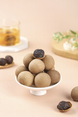 Dried Longan Fruit Traditional Chinese Snack on White Plate with Tea Background