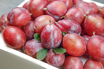 Fresh Red Plums in Bowl - Sweet Ripe Stone Fruit with Green Leaves