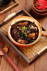 Chinese braised pork belly with preserved mustard greens in traditional clay pot with chili peppers