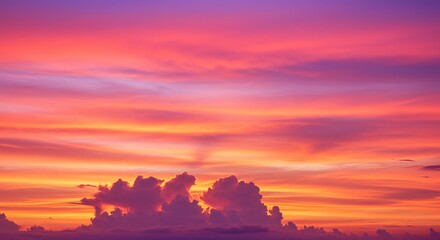 Vibrant sunset paints sky with fiery orange, pink, and purple hues over clouds