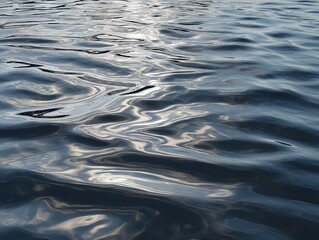 Calm water surface with intricate ripple patterns and shimmering light reflections in blue tones, creating serene aquatic texture without distinct background