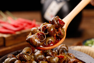 Spicy Braised Whelk and Pork Stirfry on Wooden Spoon - Traditional Asian Seafood Dish