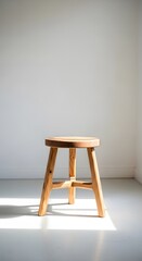 Photo of simple wooden stool with a round top and three legs, on white