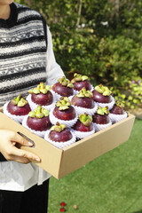Fresh Imported Mangosteen Fruit from Thailand in Wooden Box with Protective Packaging Held Outdoors