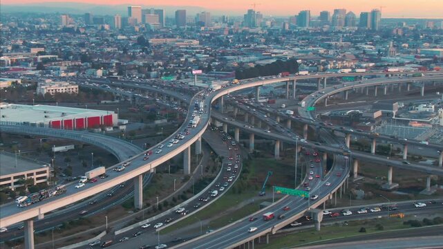 Aerial view of commuters driving cars and trucks on a complex highway interchange system during rush hour in Oakland, California, USA.