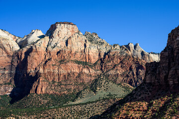 Colorful mountain peak of sedimentary rock in shades of orange against a blue sky, as a nature background, Zion National Park, Utah
