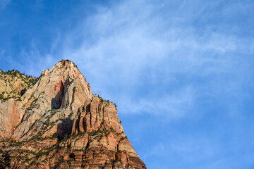 Colorful mountain peak of sedimentary rock in shades of orange against a blue sky, as a nature background, Zion National Park, Utah
