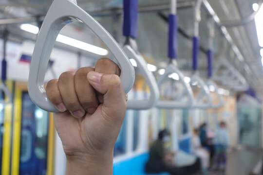 Close up of male hand holding a hand grip in commuter train