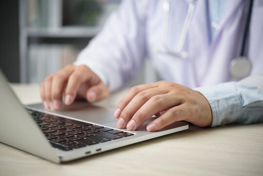 Doctor types on laptop in clinic office for EMR EHR patient record update telemedicine telehealth healthcare communication data entry workflow productivity modern hospital concept. - Powered by Adobe
