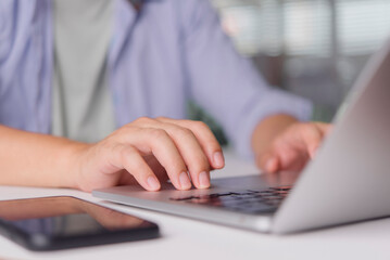 Freelancer works on laptop with smartphone at home office for remote work communication scheduling messaging cloud productivity modern workspace concept.