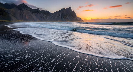 Dramatic sunset over black sand beach and volcanic mountains