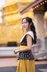 Beautiful Asian woman in retro outfit smiling at golden temple