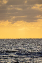A stunningly peaceful view of the expansive ocean at sunset, showcasing tranquil waters beneath a beautiful golden sky