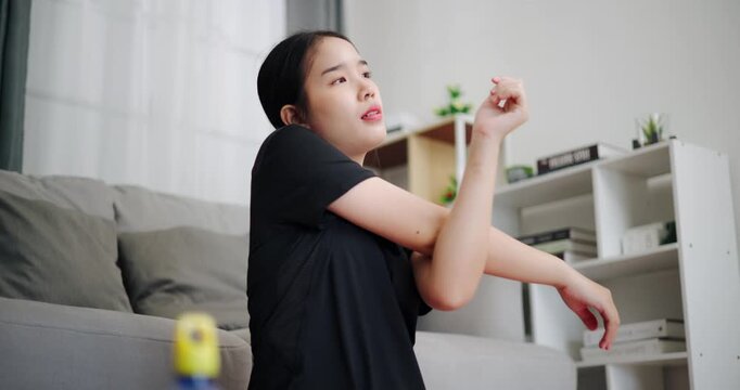 Handheld low angle view shot, Asian woman is enjoying a stretching workout on a yoga mat in living room at home. Healthy lifestyle. Women Lifestyle