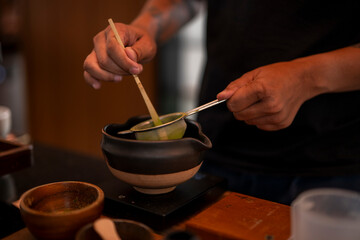 Barista preparing matcha green tea with traditional tools